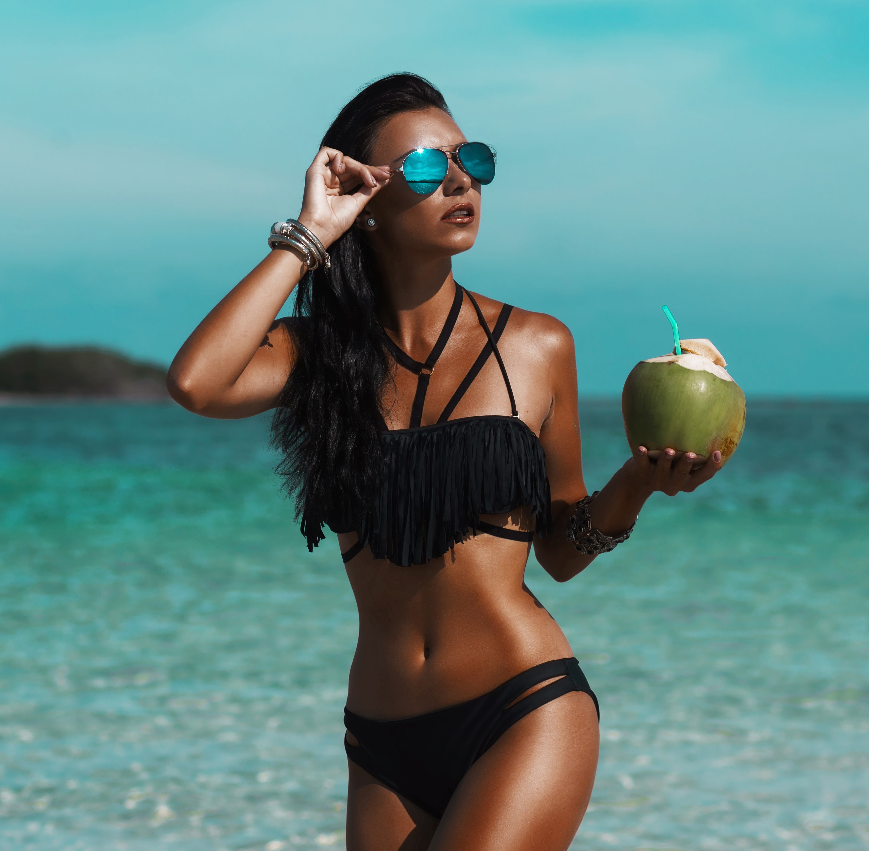 Beautiful sexy amazing young woman on the beach, excellent time, tanned radiant skin, long hair, black bikini, mirror sunglasses, fashion, glamor, vacation on a tropical island,  low key photos